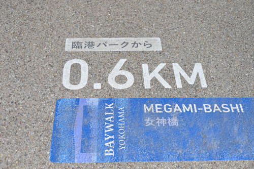 女神橋の路面にある距離案内（臨港パークから0.6キロ）